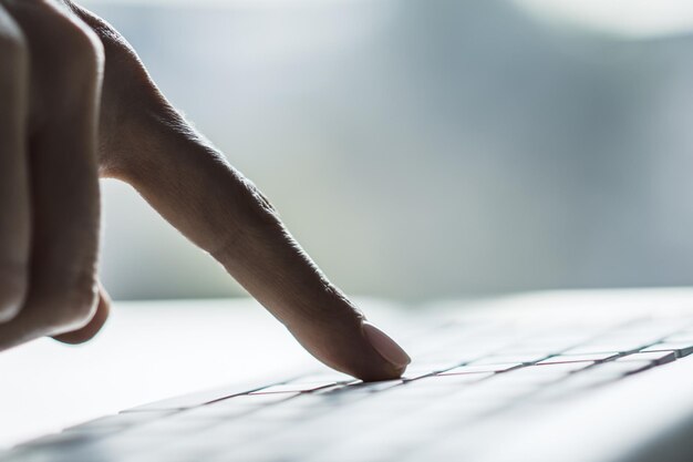 A close-up of a hand filling out an unemployment benefits application form, with a pen hovering over the signature line. The background is blurred.