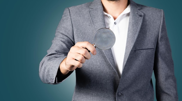 A close-up of a hand holding a magnifying glass over a Social Security card, symbolizing the detailed examination and planning required to maximize benefits. The background is blurred, focusing attention on the card and the act of investigation.