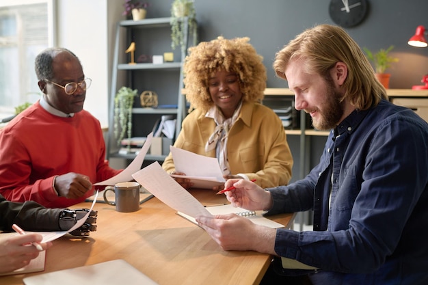 A diverse group of people collaborating around a table, reviewing a document together. The scene suggests a supportive and collaborative environment focused on improving a grant application.