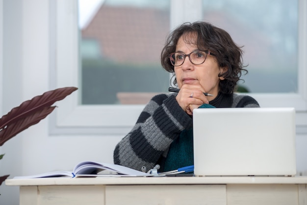 A mature student sitting at a desk, looking thoughtfully at a laptop screen while researching financial aid options. The room is quiet and focused, conveying a sense of determination and academic ambition.