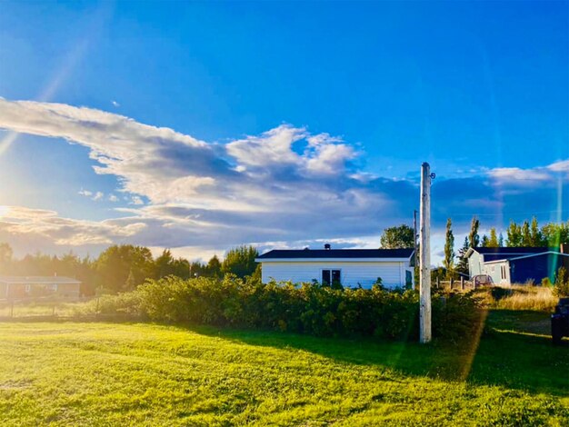 A quaint, well-maintained rural home with a porch, surrounded by green fields and a clear blue sky, symbolizing the peacefulness and affordability of rural housing.