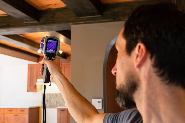 An energy auditor using thermal imaging equipment to identify areas of heat loss in a home.