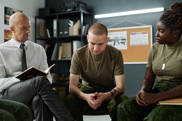 A diverse group of veterans in a classroom setting, engaged in a vocational training program. The instructor is demonstrating a hands-on skill.