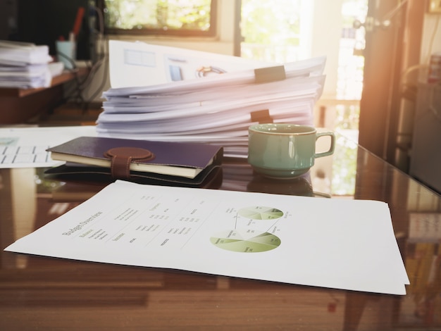 A close-up shot of application forms and financial documents spread out on a desk, with a magnifying glass hovering over them, symbolizing the careful research and preparation required for grant applications.