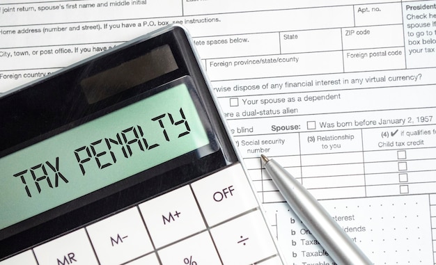 A close-up of a tax form with a calculator and a pen, highlighting the sections related to income and deductions. The focus is on the financial aspects of determining eligibility for stimulus payments.