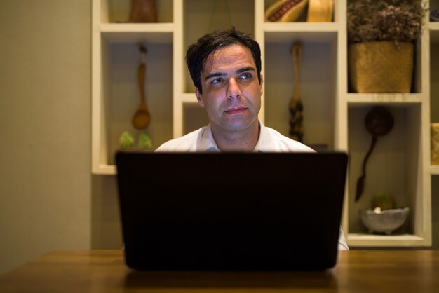 A person sitting at a desk, looking at a laptop with a website about unemployment benefits on the screen. The person's expression is hopeful and focused.