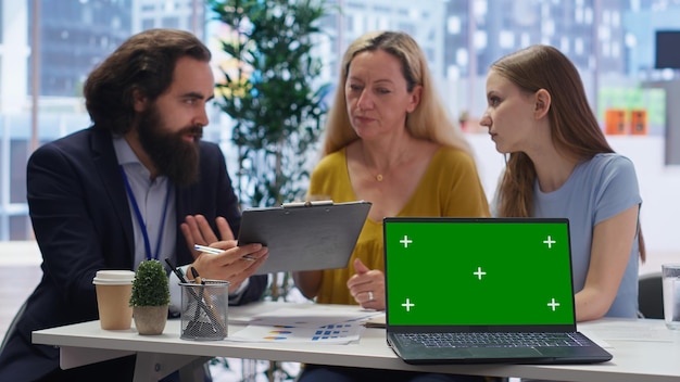People collaboratively working in a modern office, discussing data displayed on a large screen. The mood is optimistic, signifying economic growth and job creation.