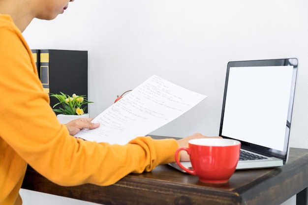 A person sitting at a desk, filling out a grant application form on a laptop, with documents and a calculator nearby.